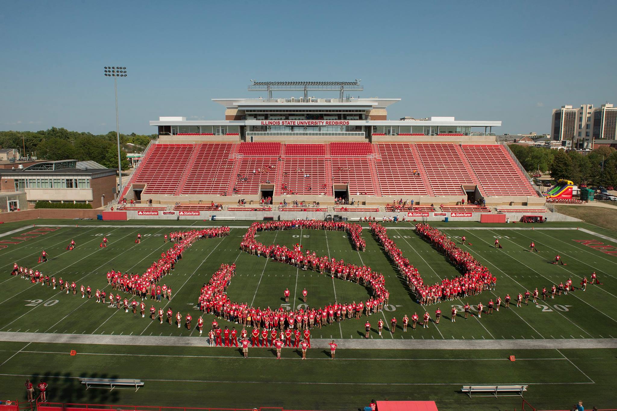 Students on football field wearing red shirts spelling out ISU
